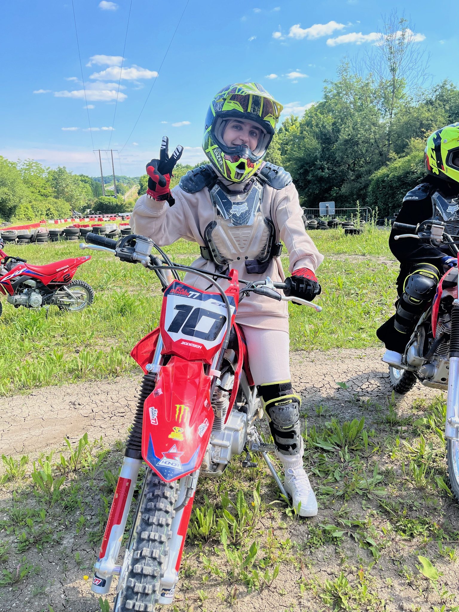 Participante casquée faisant un signe de paix sur une moto-cross